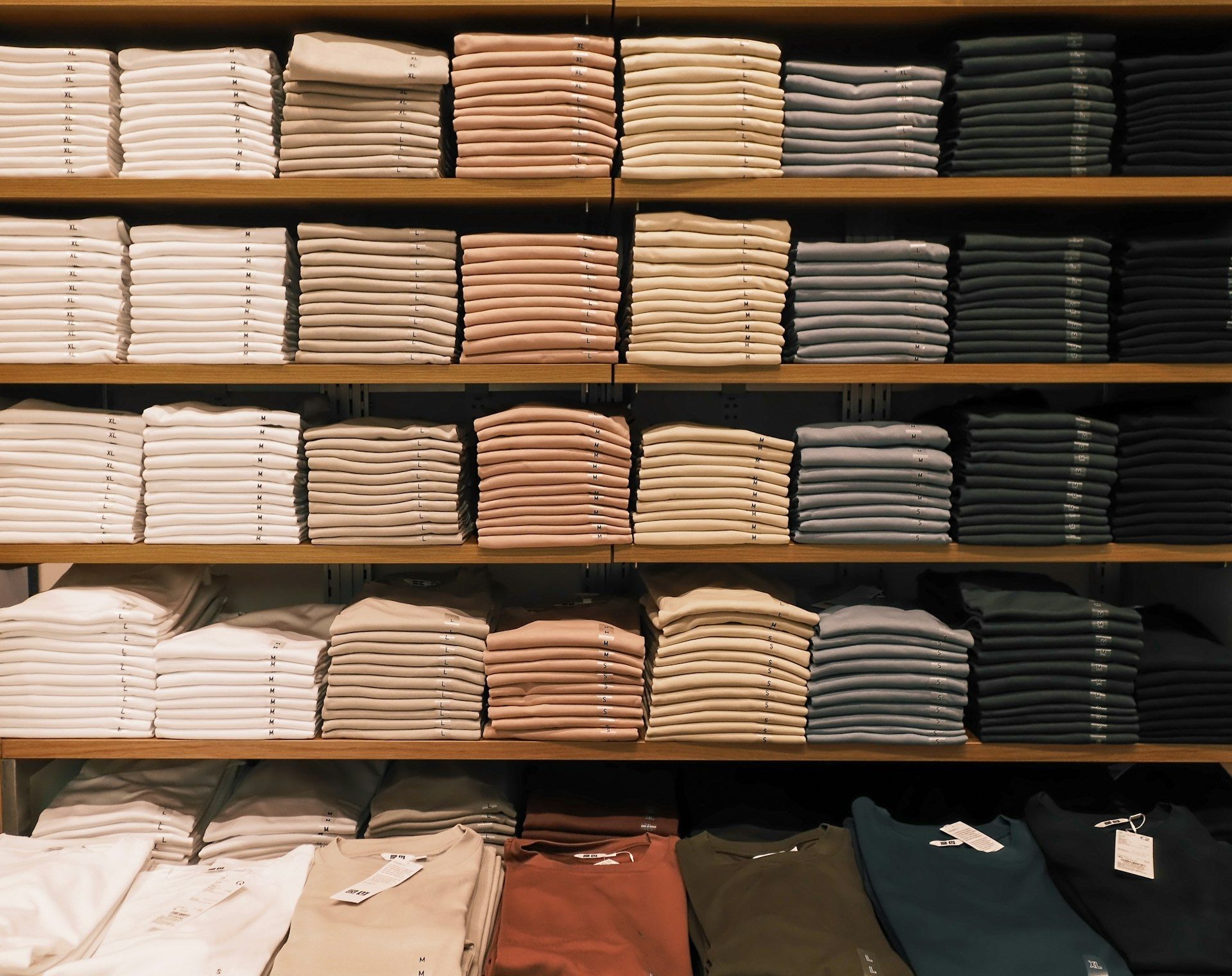 Folded knitwear and shirts sorted by colour on shelves