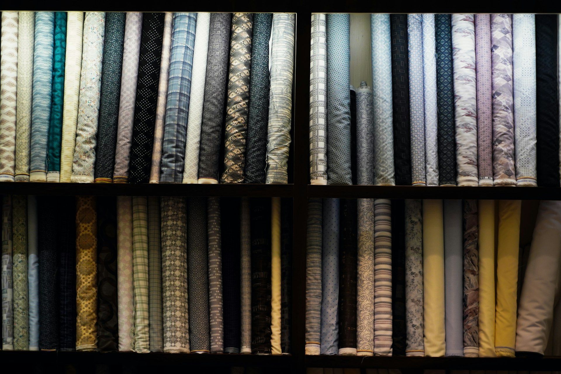 Rolled fabric sorted by shade along a display wall