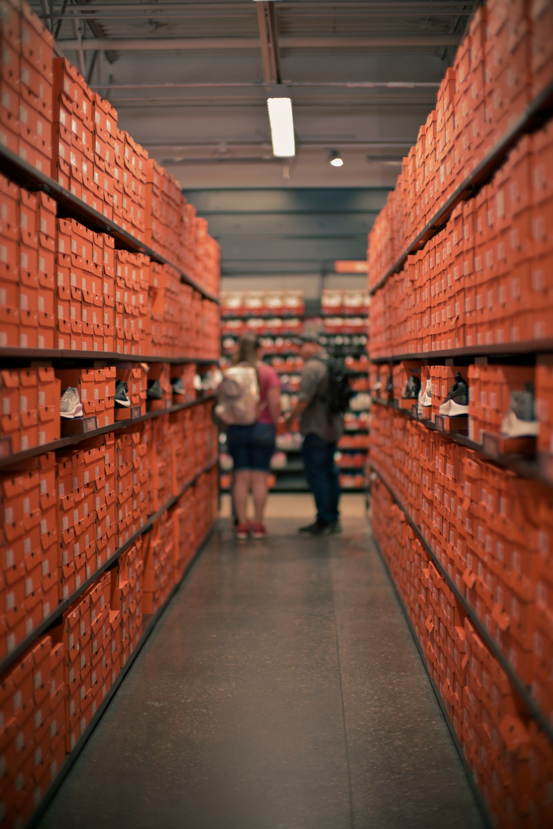 Buyers walking between rows of stacked shoe boxes