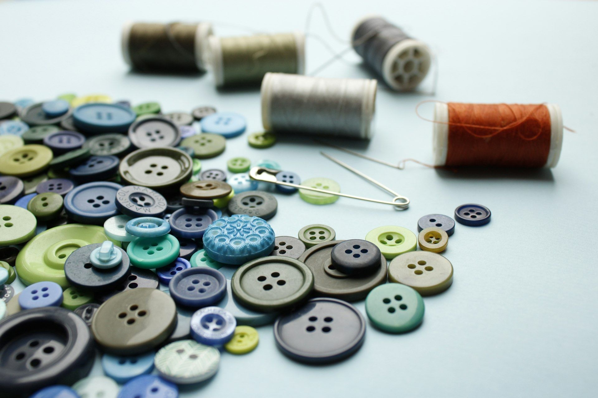 Buttons and thread spools arranged on a white surface