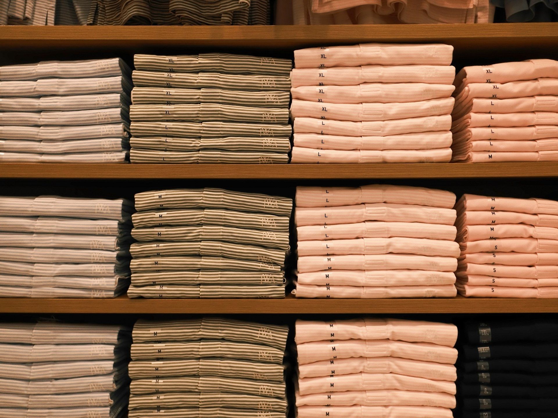 Folded shirts stacked by colour on showroom shelving
