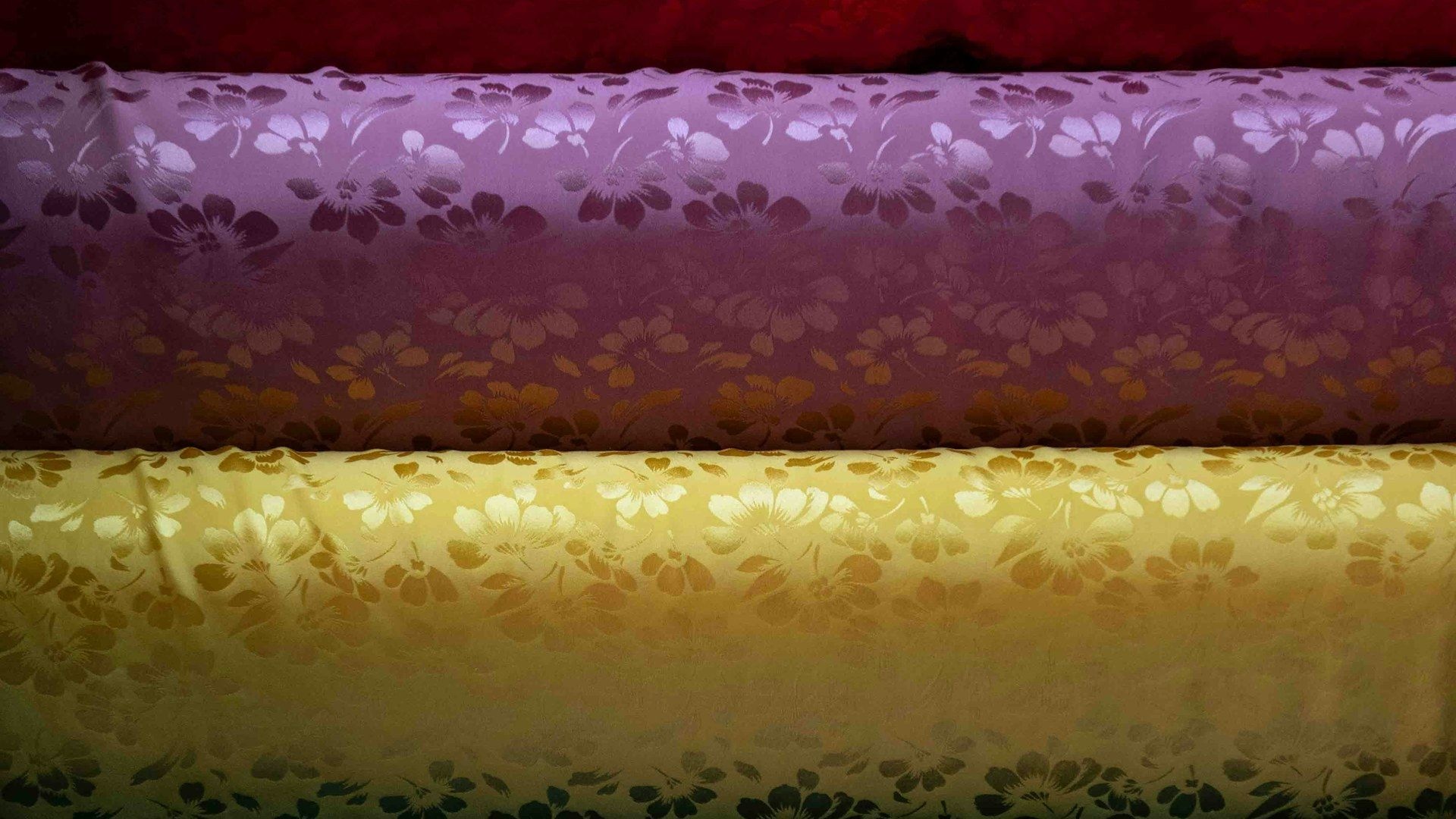 Rolls of dress fabric stacked on a wholesale market shelf
